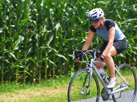 Cornfields make for good wind shelter.  Sharon demonstrates.  The downside of riding the flatlands is that the wind can be strong at times.  However, since there aren't hills here, riding into the wind takes power like hill climbing.  